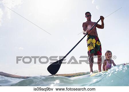 Surface level view of young man and toddler daughter standup paddleboarding View Large Photo Image Stock Photo - Surface level view of young man and toddler daughter standup paddleboarding. Fotosearch