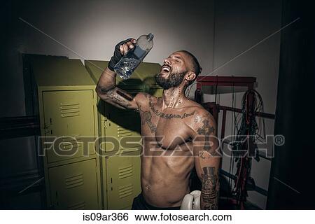Tattooed male boxer pouring water on face in gym View Large Photo Image Stock Photograph - Tattooed male boxer pouring water on face in gym. Fotosearch