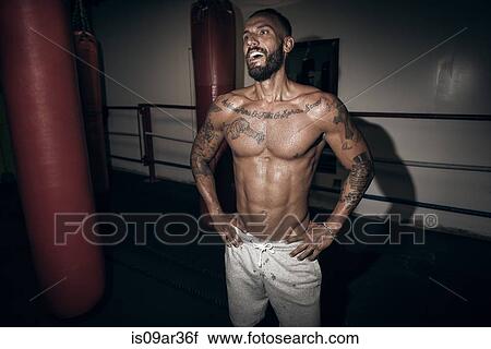 Tattooed male boxer with hands on hips laughing in gym View Large Photo Image Stock Image - Tattooed male boxer with hands on hips laughing in gym. Fotosearch