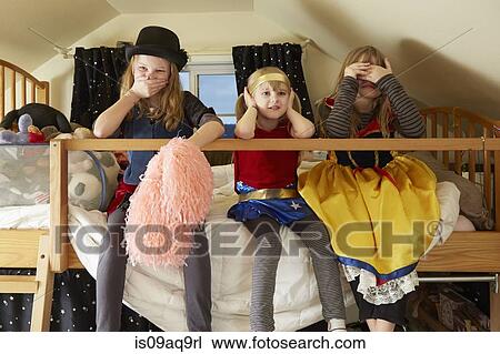 "Three sisters, sitting on bed, wearing fancy dress costumes, covering mouth, ears and eyes" View Large Photo Image Stock Image - "Three sisters, sitting on bed, wearing fancy dress costumes, covering mouth, ears and eyes". Fotosearch