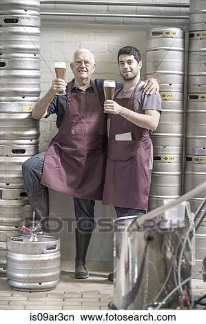 "Two brewers drinking beer in the brewery, next to kegs" View Large Photo Image Picture - "Two brewers drinking beer in the brewery, next to kegs". Fotosearch