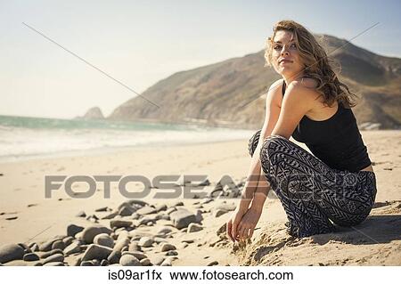 Stock Photo - "Woman relaxing on beach, Malibu, California, USA". Fotosearch