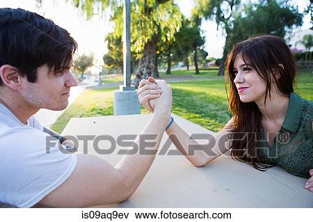 Young couple arm wrestling at picnic bench in park View Large Photo Image Stock Photo - Young couple arm wrestling at picnic bench in park. Fotosearch