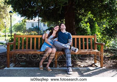 Young couple looking up from park bench View Large Photo Image Stock Photography - Young couple looking up from park bench. Fotosearch