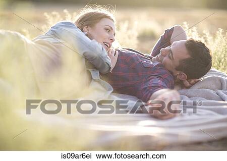Young couple lying outdoors on blanket smiling View Large Photo Image Stock Image - Young couple lying outdoors on blanket smiling. Fotosearch