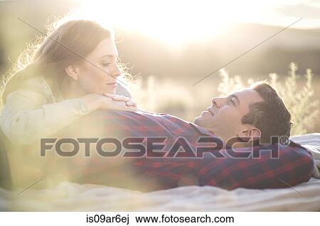 Stock Image - Young couple lying outdoors on blanket relaxing. Fotosearch