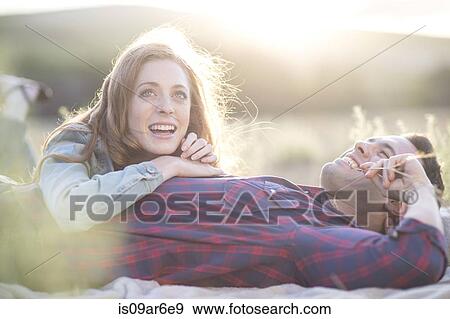 Stock Photo - Young couple lying together chewing straw grass. Fotosearch