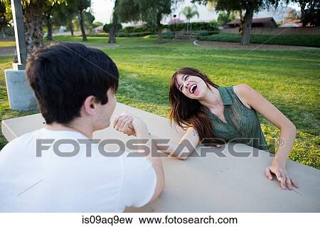 Young couple pretending to arm wrestle at picnic bench in park View Large Photo Image Stock Photo - Young couple pretending to arm wrestle at picnic bench in park. Fotosearch