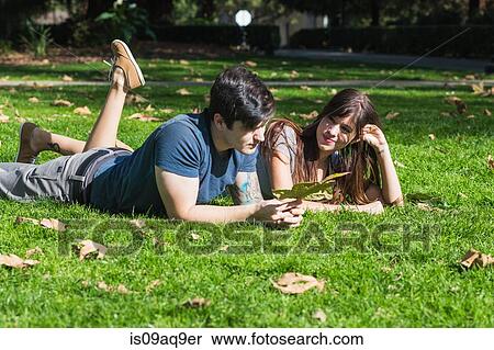 Young couple with autumn leaf lying in park View Large Photo Image Stock Photography - Young couple with autumn leaf lying in park. Fotosearch