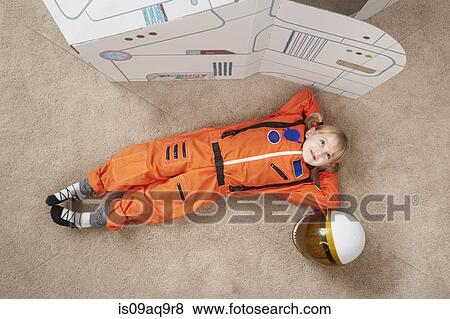 "Young girl playing, wearing astronaut outfit, lying next to cardboard spaceship, elevated view" View Large Photo Image Stock Photo - "Young girl playing, wearing astronaut outfit, lying next to cardboard spaceship, elevated view". Fotosearch