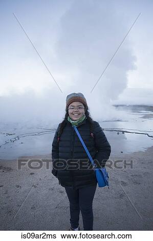 Stock Photograph - "Young girl standing in front of Tatio Geyser, smiling, San Pedro. Atacama. Chile". Fotosearch