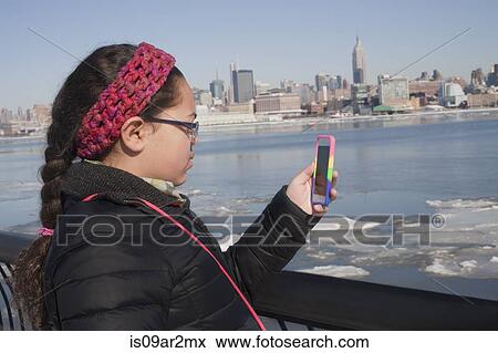 "Young girl taking photograph of skyline using smartphone, New York, NY, USA" View Large Photo Image Stock Photo - "Young girl taking photograph of skyline using smartphone, New York, NY, USA". Fotosearch