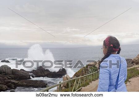 "Young girl watching waves crash on rocks, Valparaiso, Chile" View Large Photo Image Stock Photograph - "Young girl watching waves crash on rocks, Valparaiso, Chile". Fotosearch