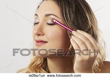 Picture - Young woman applying eyeshadow. Fotosearch