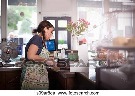 Stock Image - Bakery owner placing cake into box. Fotosearch