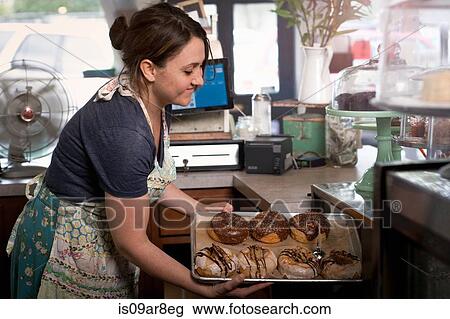 Bakery owner placing tray of doughnuts into display case View Large Photo Image Stock Image - Bakery owner placing tray of doughnuts into display case. Fotosearch