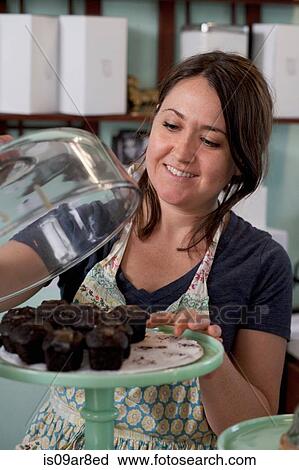 Bakery owner taking cupcake from cakestand View Large Photo Image Stock Image - Bakery owner taking cupcake from cakestand. Fotosearch