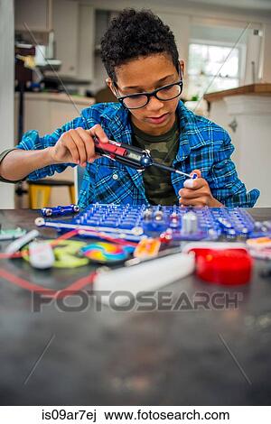 Stock Image - Boy working on science project at home. Fotosearch