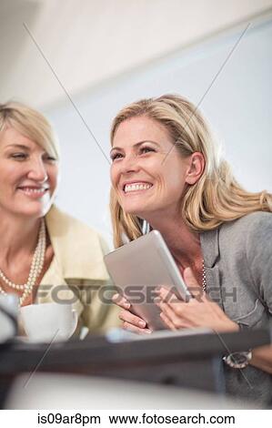 Picture - Business woman using digital tablet at business lunch. Fotosearch