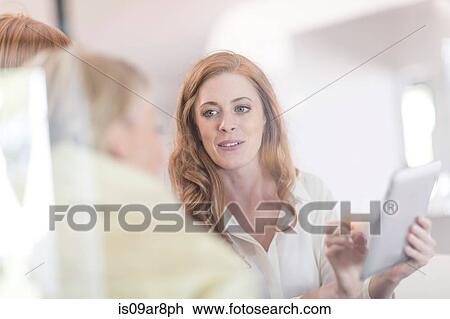 Stock Image - Business woman using digital tablet at business lunch. Fotosearch