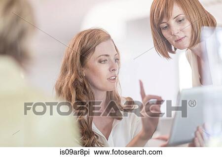 Stock Image - Business woman using digital tablet at business lunch. Fotosearch