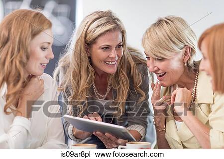 Stock Image - Business woman using digital tablet at business lunch. Fotosearch