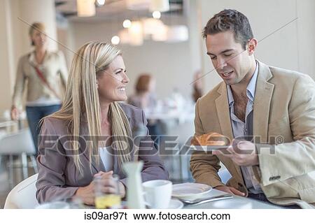 Businessman handing croissant to colleague at breakfast in hotel restaurant View Large Photo Image Stock Photograph - Businessman handing croissant to colleague at breakfast in hotel restaurant. Fotosearch