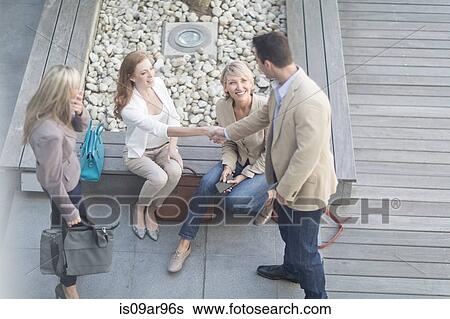 Stock Photograph -  Businessman shaking hands with businesswomen on hotel terrace. Fotosearch