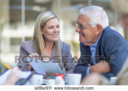 Stock Image - Businesswoman and man talking at coffee break on hotel terrace. Fotosearch