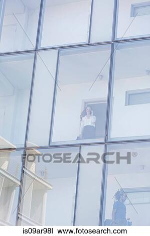 Businesswoman looking leaving room of glass fronted hotel whilst talking on smartphone View Large Photo Image Stock Image - Businesswoman looking leaving room of glass fronted hotel whilst talking on smartphone. Fotosearch