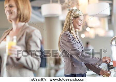 Picture - Businesswoman pouring fruit juice in hotel restaurant. Fotosearch