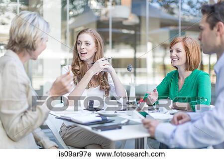 Stock Image - Businesswomen and man meeting at coffee break on hotel terrace. Fotosearch