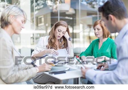 Stock Image - Businesswomen and man preparing paperwork on hotel terrace. Fotosearch