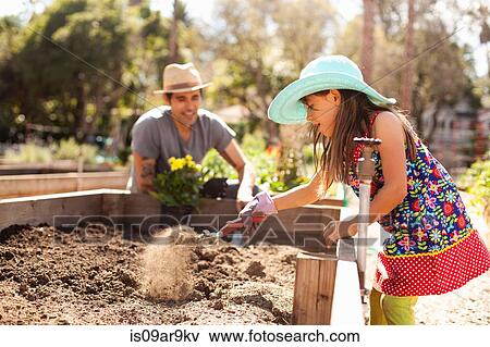 Stock Photo - Enthusiastic girl digging flower bed in community garden. Fotosearch