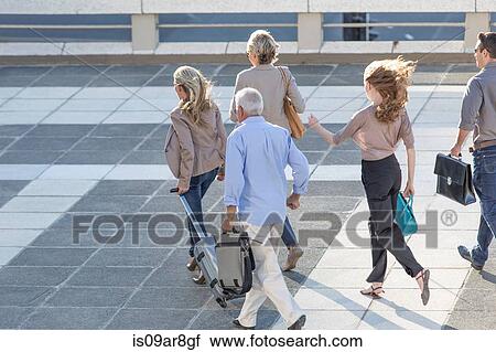Stock Image - Five adults walking across paving slabs. Fotosearch