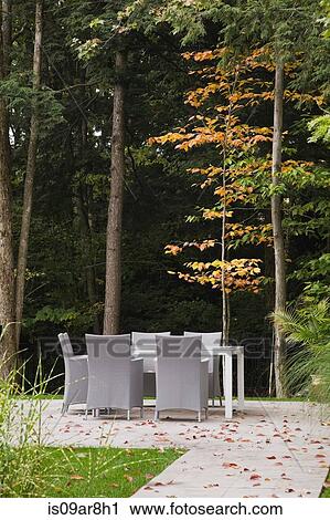 Stock Image - Flagstone path leading to table and chairs in landscaped backyard in autumn, Quebec, Canada. Fotosearch