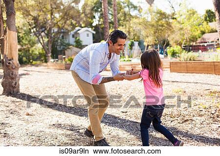 Girl and father playing in community garden View Large Photo Image Picture - Girl and father playing in community garden. Fotosearch