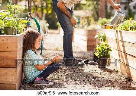Girl crouching in community garden using smartphone View Large Photo Image Stock Photography - Girl crouching in community garden using smartphone. Fotosearch