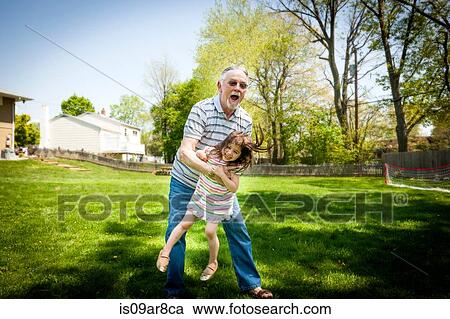 Stock Image - Grandfather and granddaughter playing in garden. Fotosearch