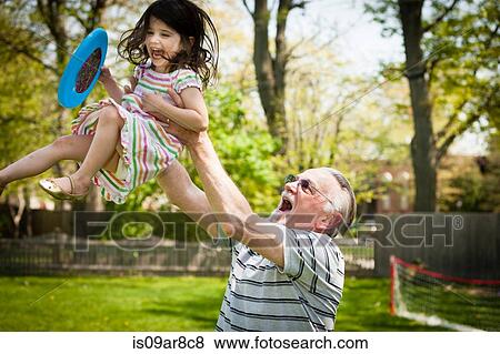 Stock Photo - Grandfather and granddaughter playing in garden. Fotosearch