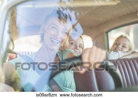 Picture - Grandmother driving car, granddaughters sitting in back seat. Fotosearch
