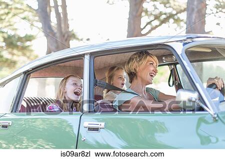 Stock Image - Grandmother driving car, granddaughters sitting in back seat. Fotosearch