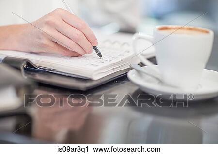 Stock Image - Hand of business person writing into diary. Fotosearch