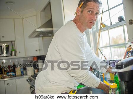 Stock Image - Handyman using kitchen sink. Fotosearch