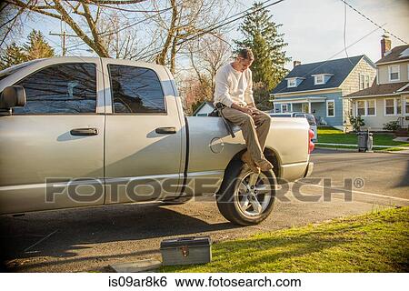 Handyman using smartphone on rear of truck View Large Photo Image Stock Photograph - Handyman using smartphone on rear of truck. Fotosearch
