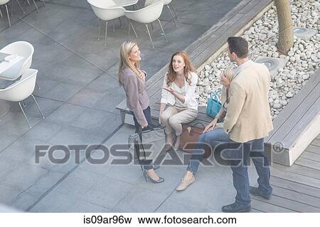 Stock Photo - High angle view of businessman and women chatting on hotel terrace. Fotosearch