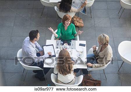 Stock Photo - High angle view of businessmen and businesswomen having lunch meeting on hotel terrace. Fotosearch