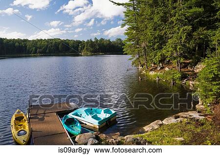 Stock Photo - Kayaks and paddle boat tied to dock on lake, Quebec, Canada. Fotosearch
