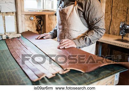 Leather craftsman with strips of leather on workshop bench View Large Photo Image Picture - Leather craftsman with strips of leather on workshop bench. Fotosearch