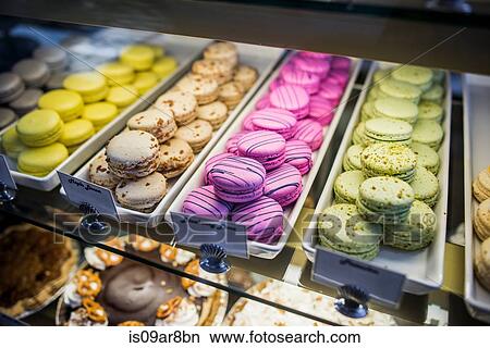 Picture - Macarons in trays in display cabinet, close-up. Fotosearch
